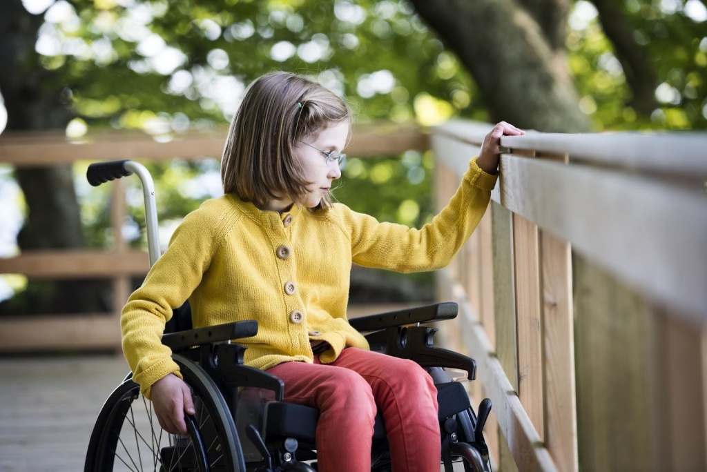 Маленькая девочка в инвалидной коляске